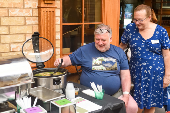 Wendy and Ray stand together while Ray stirs his Irish Coddle Soup in the crock pot. 