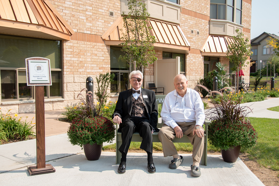 Ron Schlegel and Ron Posno sit together on the #ElderWisdom green bench outside of The Village of Glendale Crossing.