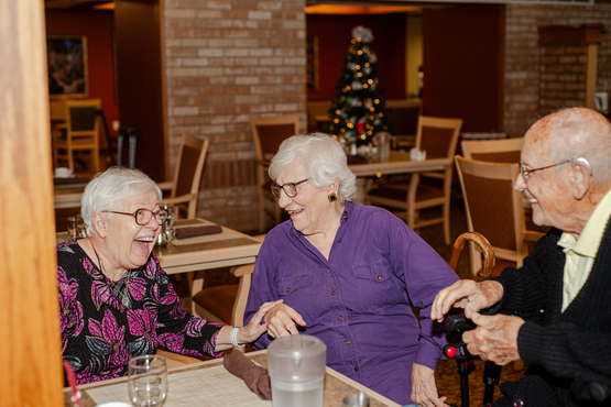 Erika, Anne and Bruno share a laugh around the dining table at The Village of Taunton Mills. 