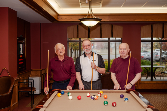 Lou, Mike and Roy pose behind the pool table at Taunton Mills, cues in hand. 