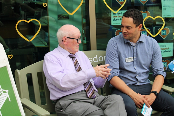 Dennis sits upon the Green Bench at the Whitby Farmer's Market conversing with Taunton Mills general manager Dan Kennedy.