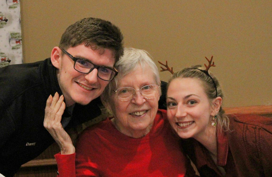 Two team members are pictured alongside a resident during Christmas festivities at University Gates.