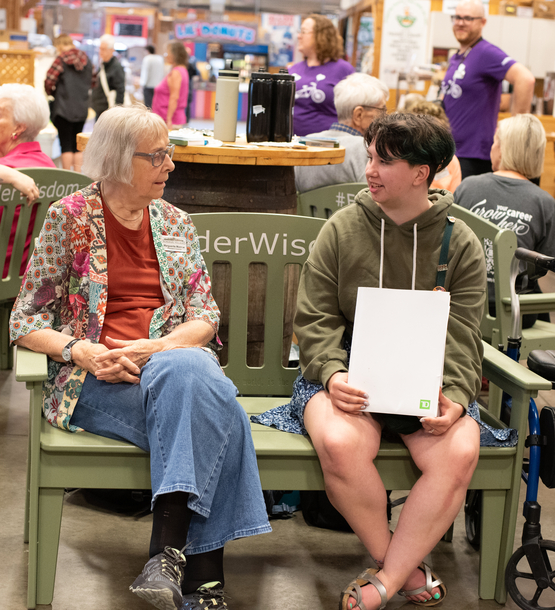 A student sits with an elder upon the Green Bench during an ElderWisdom event at a school.