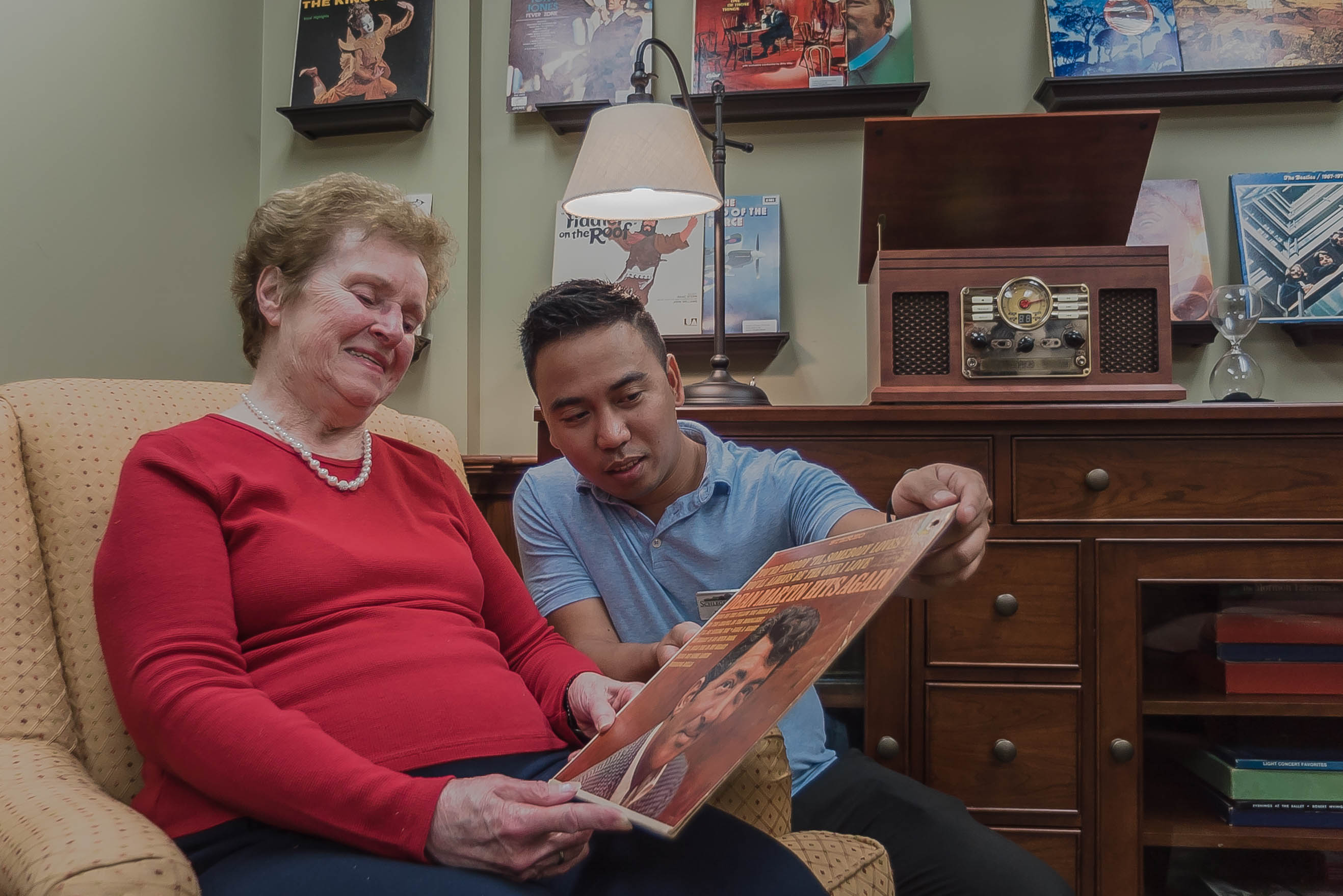 Resident with team member looking a record album cover in the Memory Care Neighbourhood