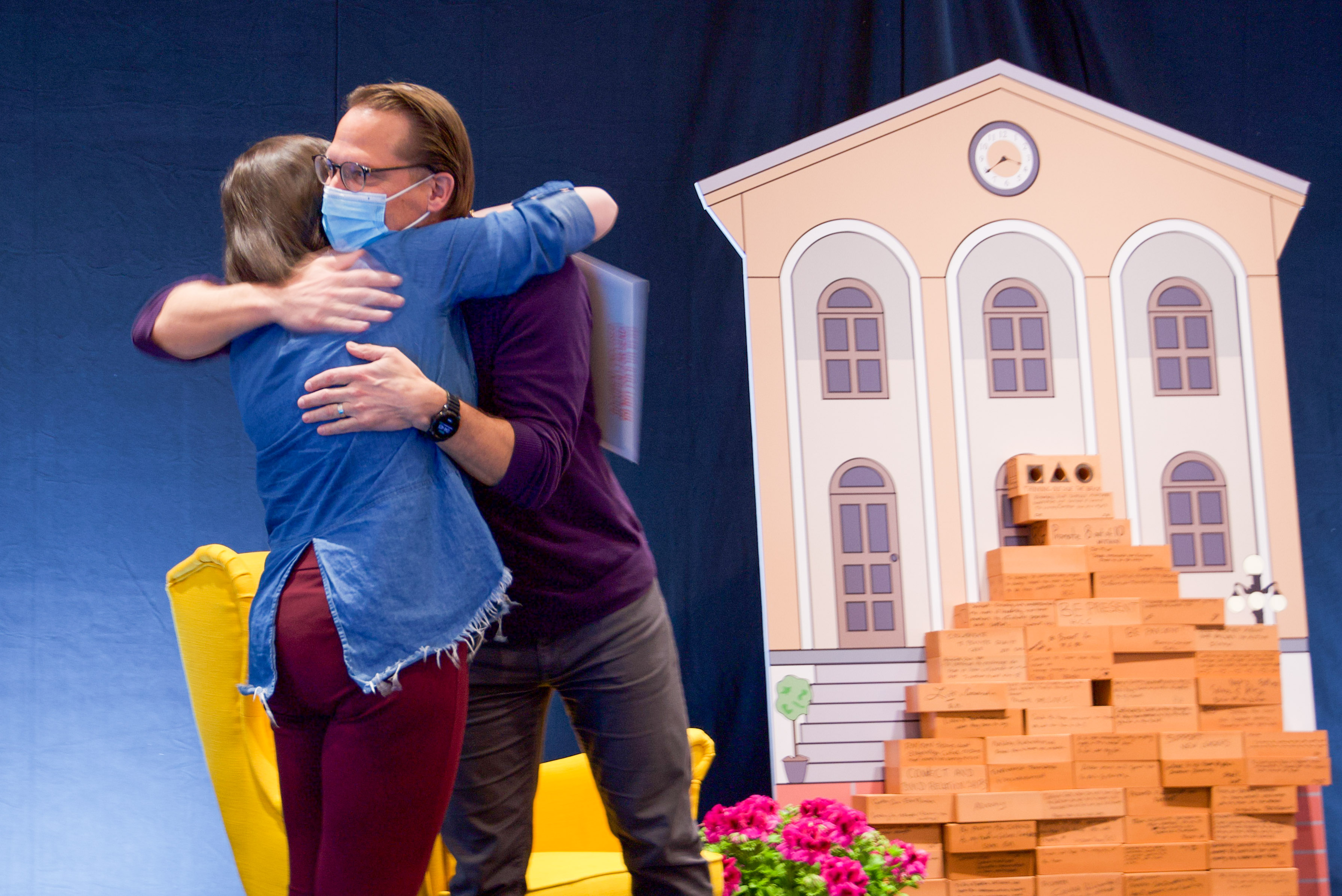 Jamie Schlegel and a fellow leader embrace on the stage at the annual leadership retreat. 