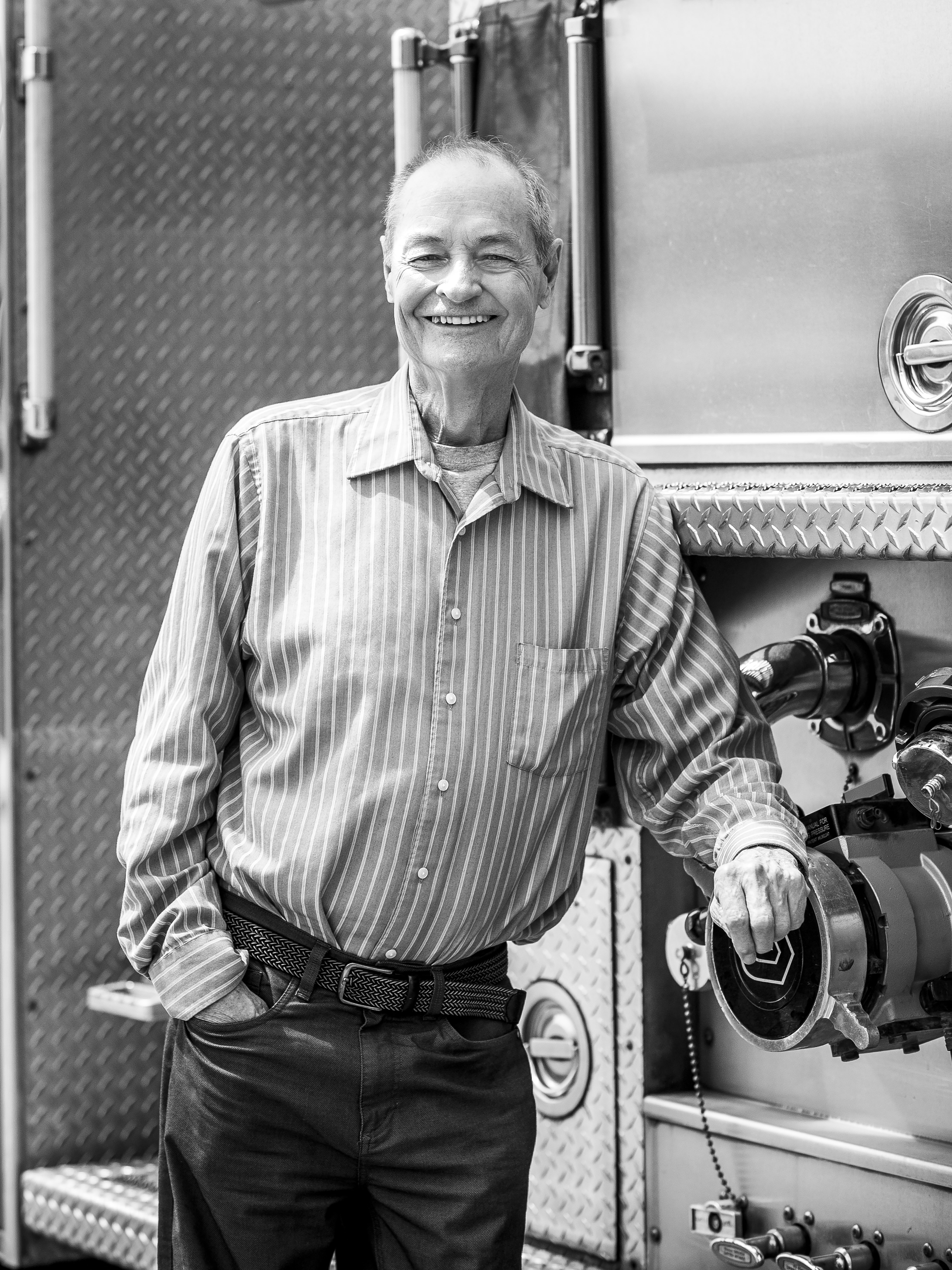 Ron Seanor black and white portrait posing with a firetruck