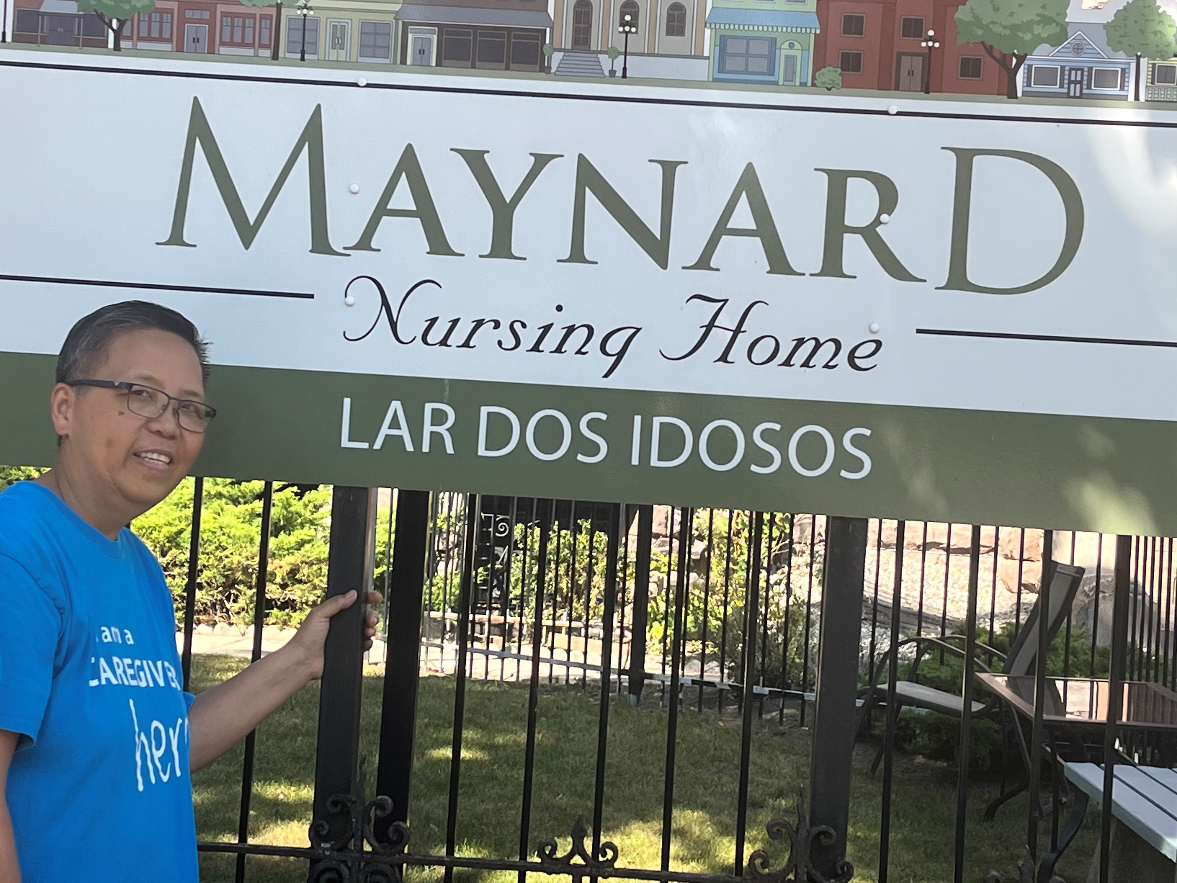 Lou stands beside the sign for Maynard Nursing Home.