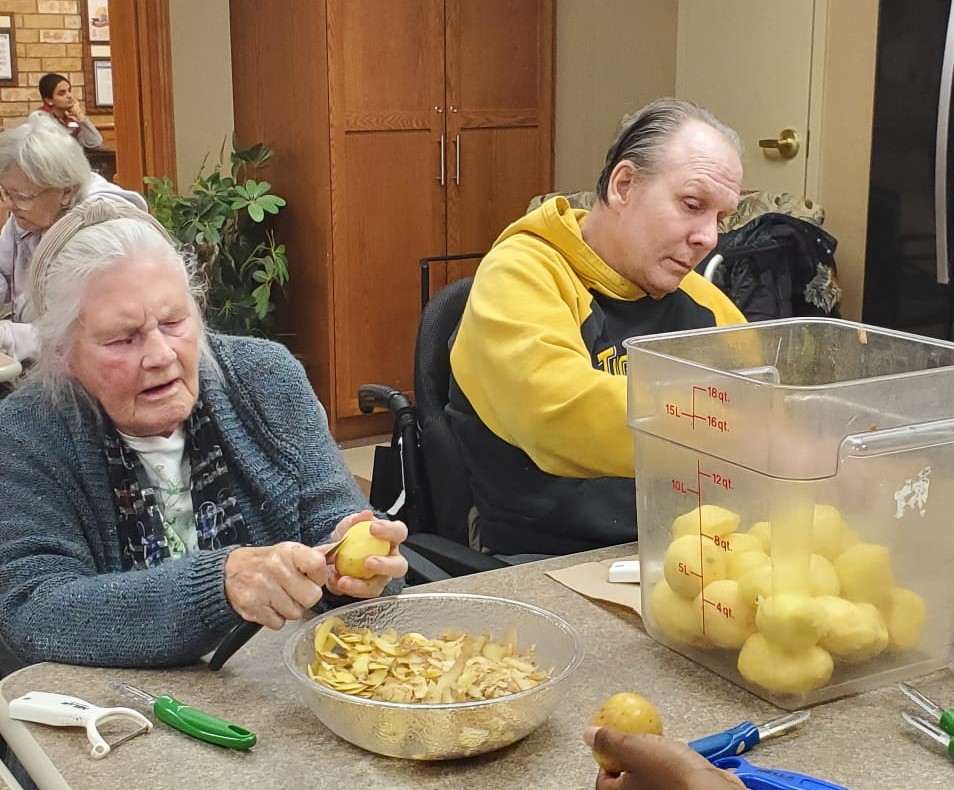 Residents from The Village at University Gates peel potatoes in preparation for their holiday feast. 