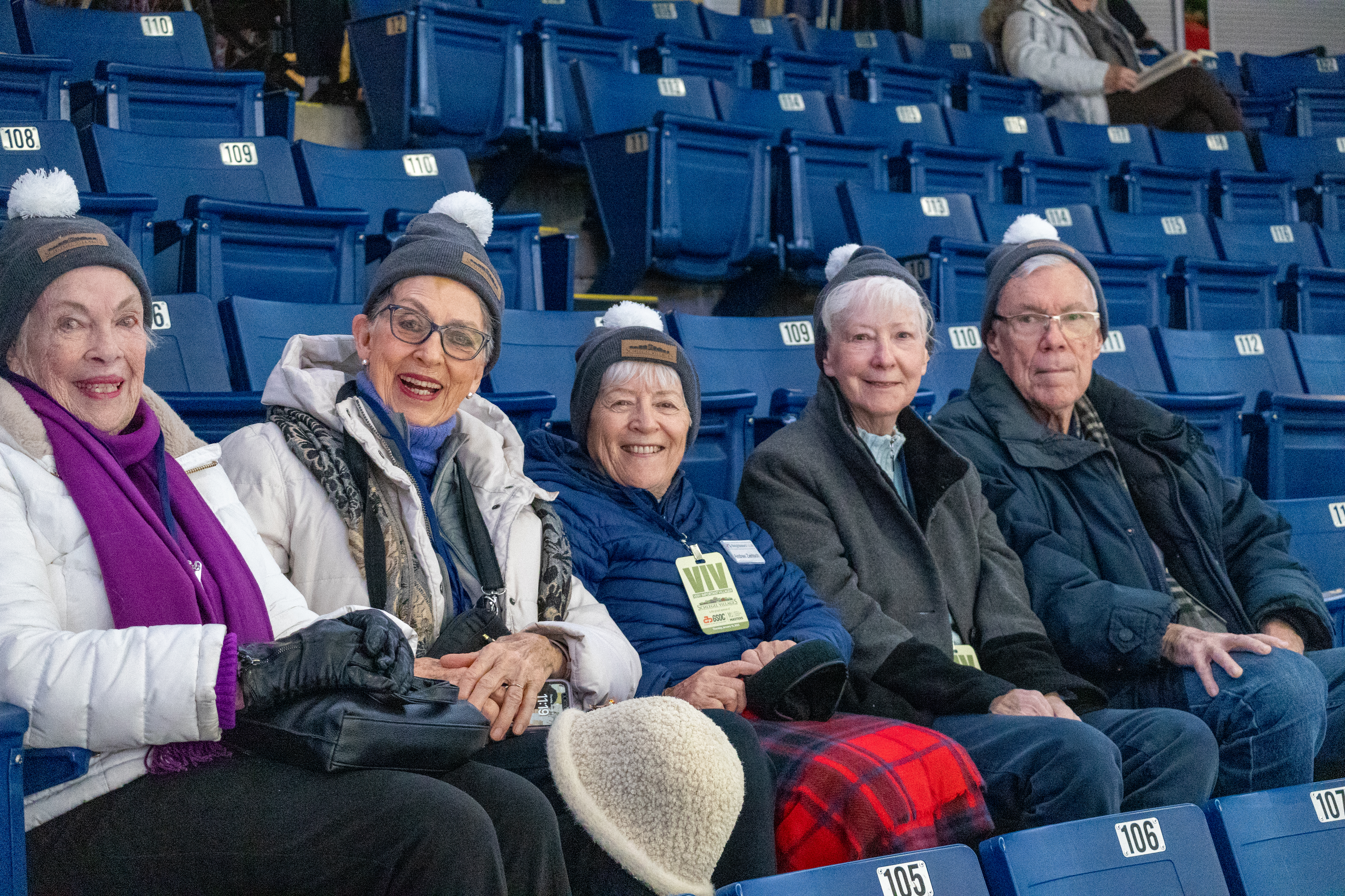 Curling fans with their Schlegel toques smile for the camera in their seats at the Sleeman Centre. 