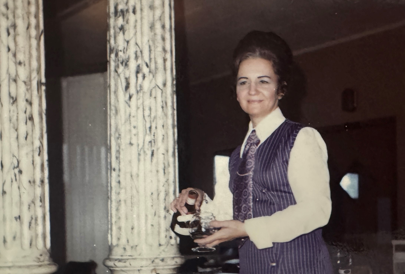 Lena is captured in an old photo pouring a drink while working at the hotel she owned and operated with her husband and family. 