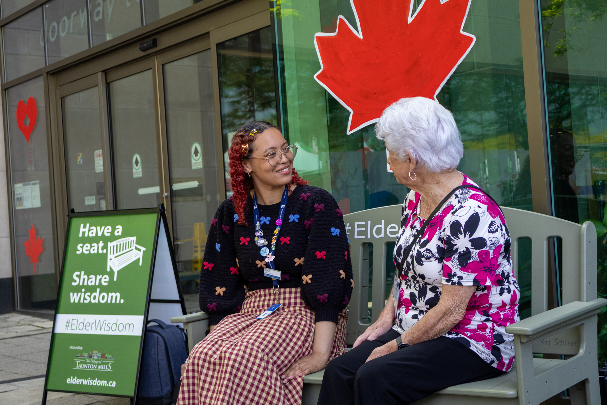 Sybil and a student from the Whitby Library sit upon the Green Bench and share a conversation. 