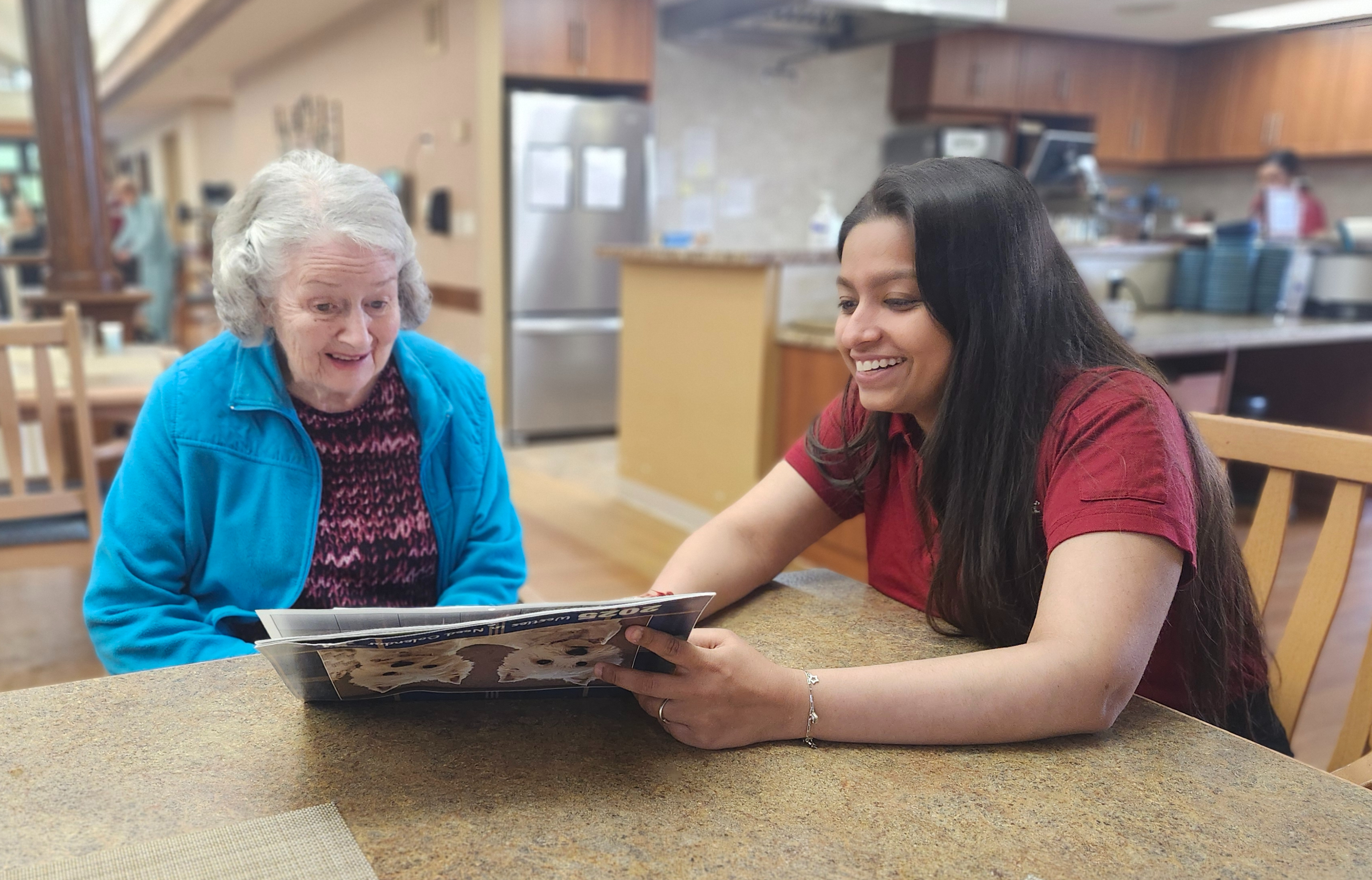 Devanshi sits at a table alongside a resident while they read together. She is always seeking new opportunities to engage with residents. 