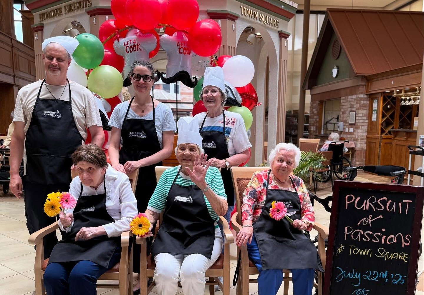 Resident chefs, family members and volunteers pose in their Pursuit of Passions aprons during the Humber Heights "Timeless Recipes, Endless Stories" event. 
