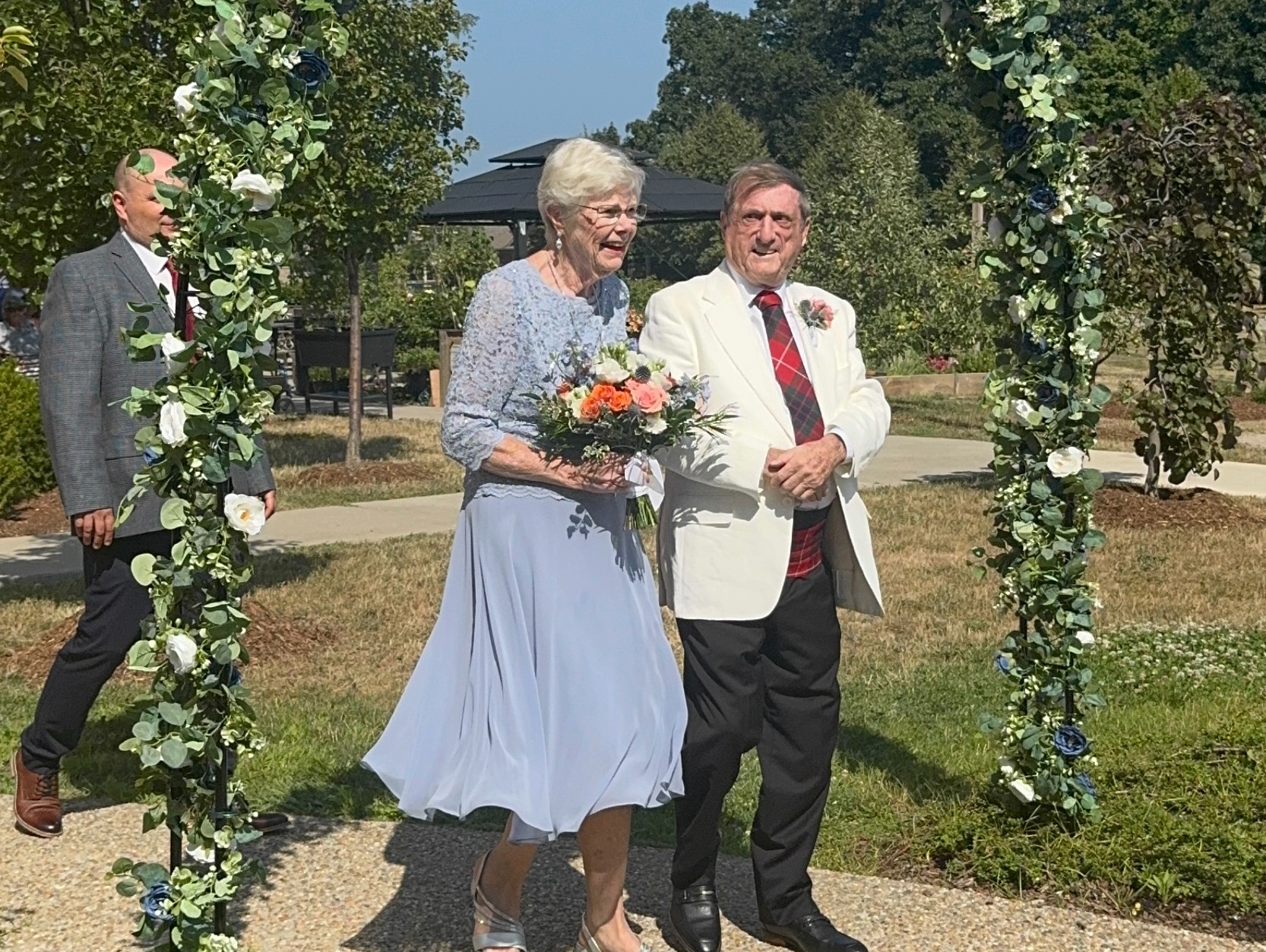 Beverley and Richard walking down the aisle in their outdoor wedding at The Village of Tansley Woods. 