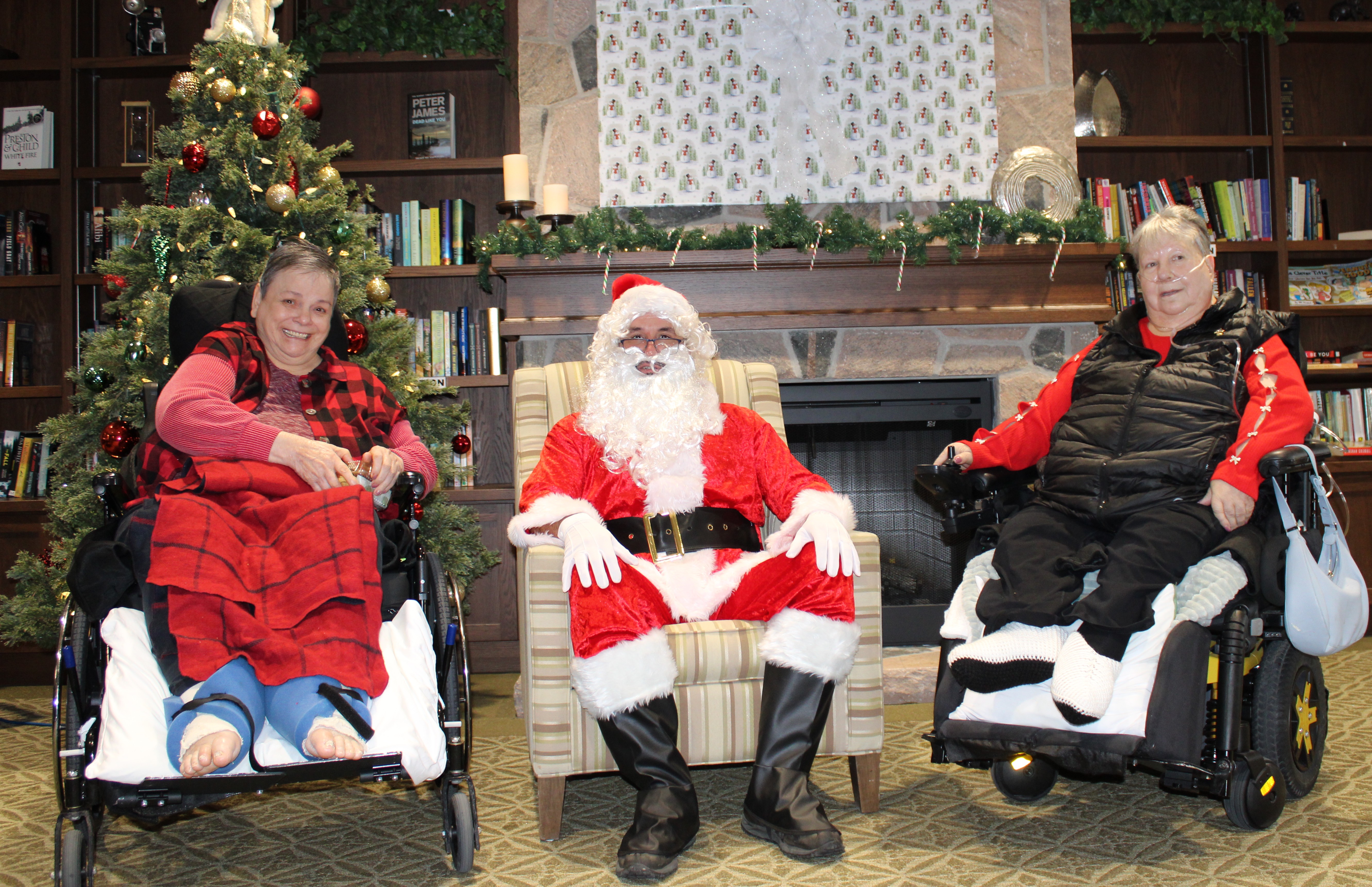 Brenda and Barb from University Gates is pictured by a Christmas tree with Santa Claus.