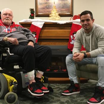 William sitting in his wheelchair and Jake sitting in a chair wearing matching red sneakers