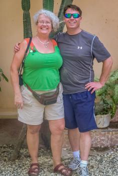 Barb Sutcliffe and Bill Cummings standing and posing for a photo in Haiti wearing shorts and t-shirts
