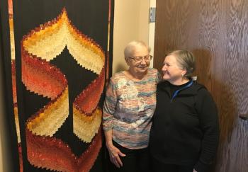 Irma's beautiful quilting artistry adorns her wall as she  shares love with her daughter, Carol. 