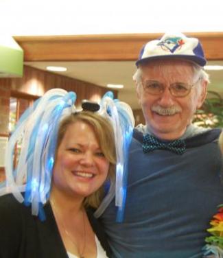 Melanie wearing a silly head piece and Merv wearing a baseball cap