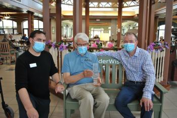 Ted Hudson (left) and Bryce McBain, General Manager at The Village of Riverside Glen (right), present Lloyd Hetherington with an award marking 10,000 downloads of the Stories from  the Green Bench Podcast, which Lloyd co-hosts. 